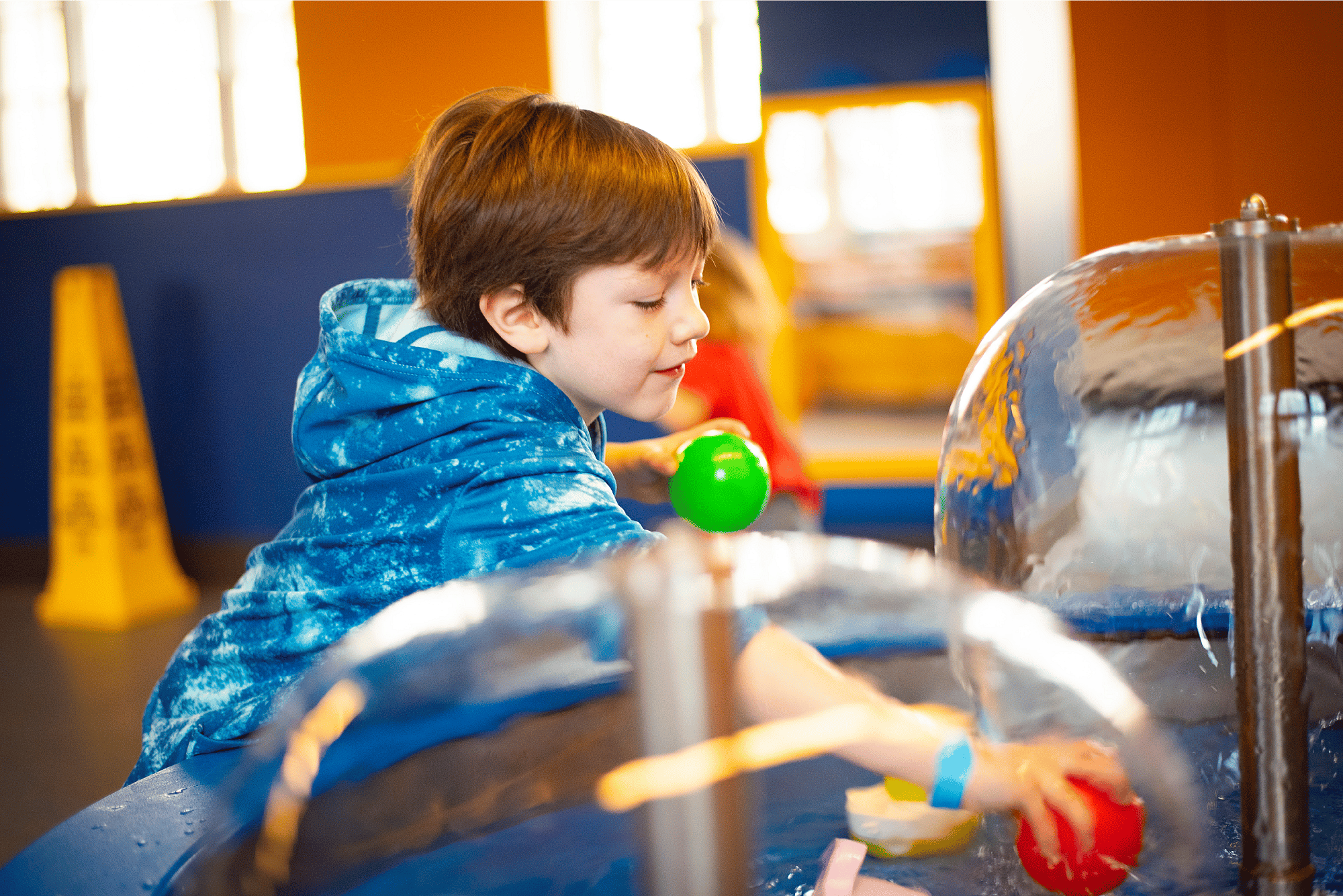 A child is seen playing with water in COSI's little kid space.