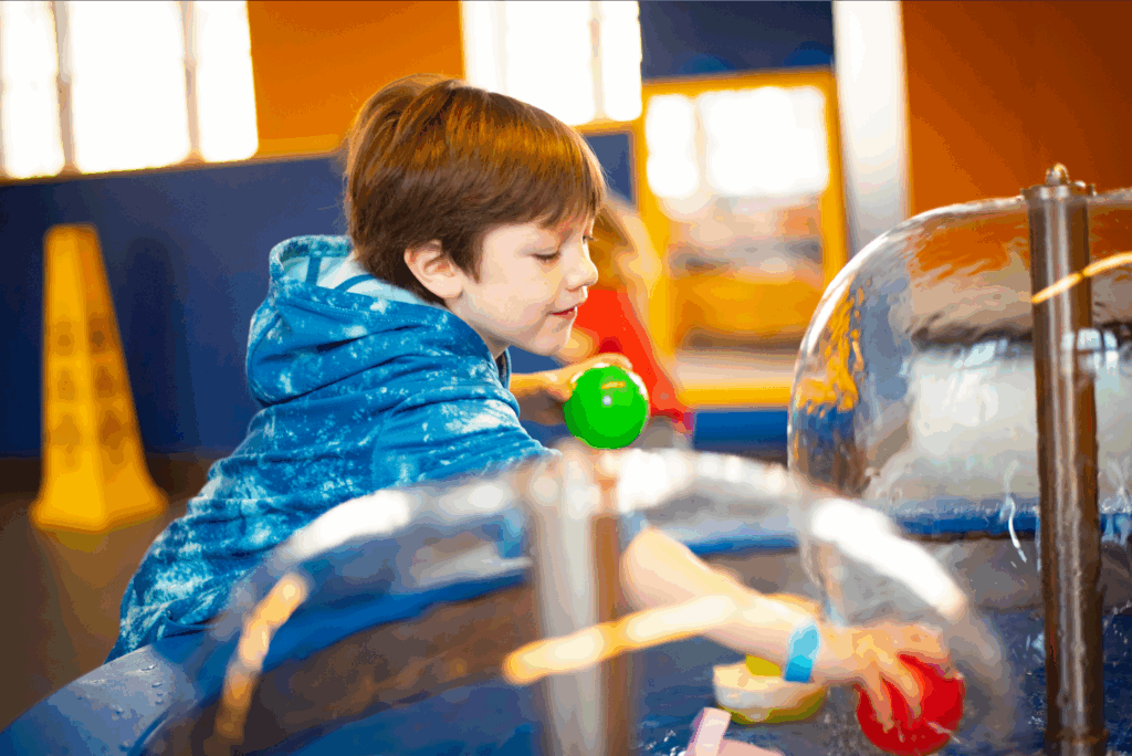 A child is seen playing with water in COSI's little kid space.
